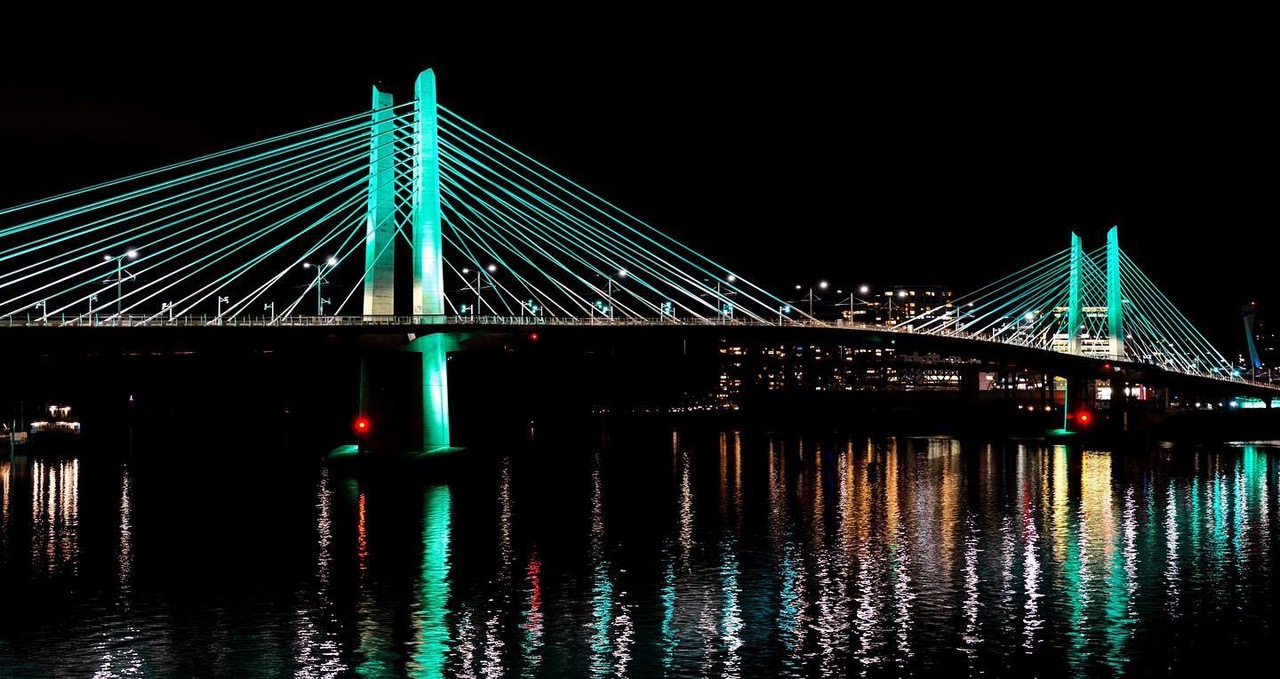 An illuminated cable-stayed bridge and its reflections at night
